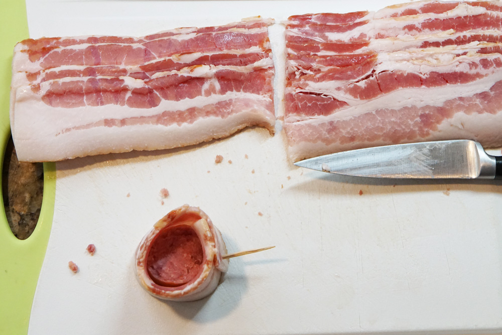 bacon cut in half and wrapped around a piece of sausage.