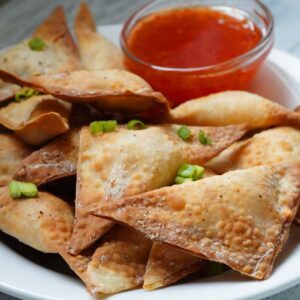 Jalapeno popper wontons on a plate with dipping sauce.