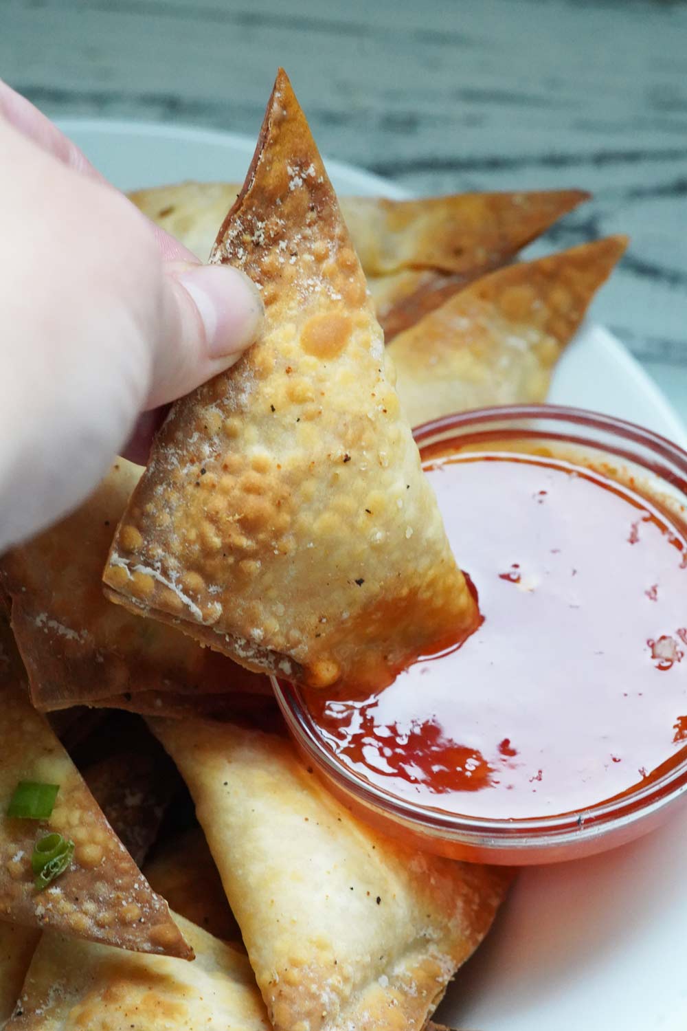 Jalapeno popper wontons on a plate with dipping sauce.