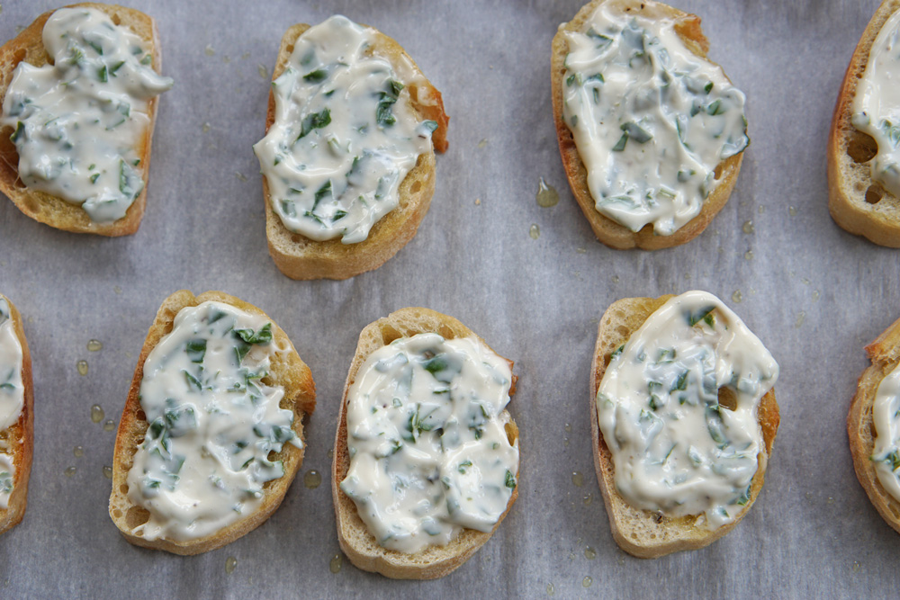 topping the bread with mayo and basil