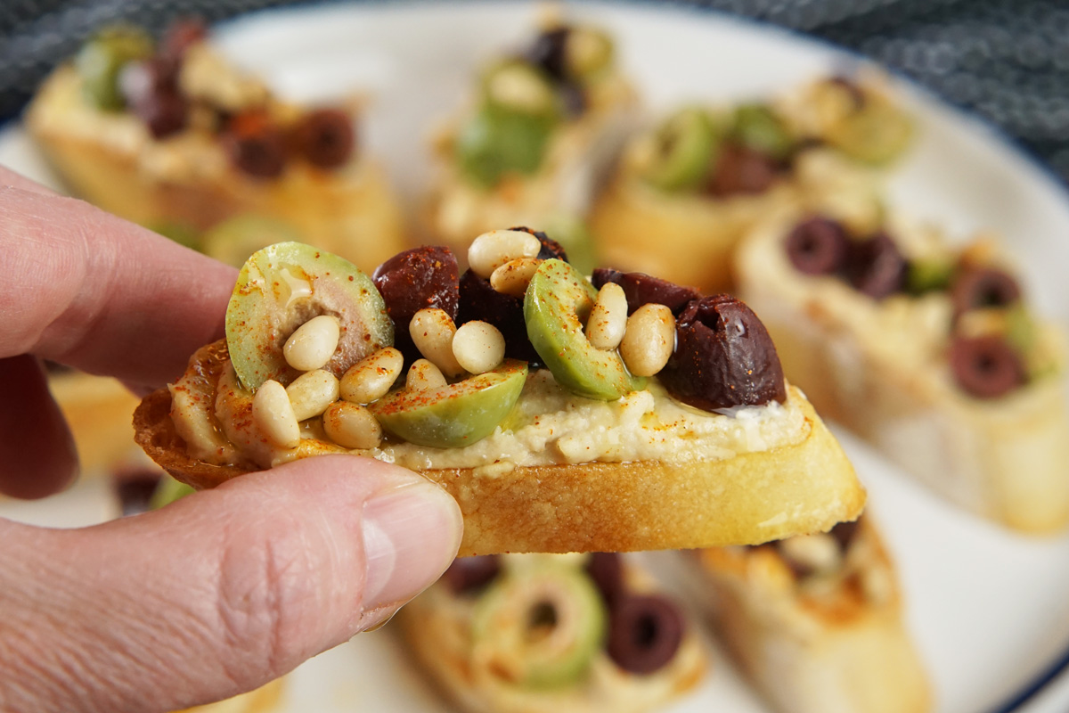 Hummus Crostini with Olives & Pine Nuts